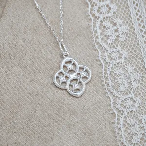 Vue détaillée d'un pendentif vintage en argent S925 ajouré sur un tissu beige texturé