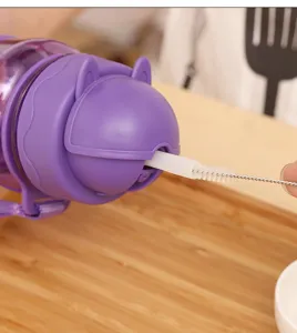 Gros plan d'un goupillon pour paille nettoyant la paille d'une gourde violette.