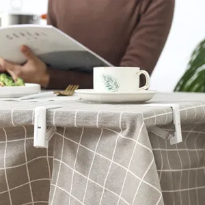 Set di 4 clip per tovaglia bianche antiscivolo su una moderna tovaglia a scacchi grigia