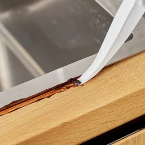 White crevice cleaning brush for scrubbing narrow gaps between sink and countertop.