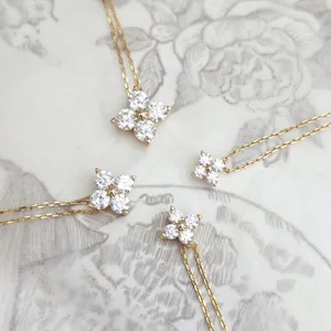 Close-up detail of moissanite clover necklaces in various sizes on floral background