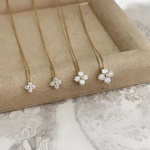 Detailed close-up of four moissanite clover necklaces on a beige jewelry tray