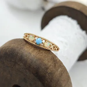 Close-up detail of retro S925 silver gold-plated ring set with natural turquoise and opal stones