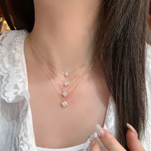 Detailed view of layered gold-plated clover moissanite pendants on a model's neck