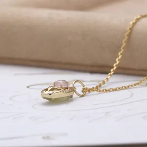 Close-up detail of double-sided rose quartz and prehnite pendant in gold setting