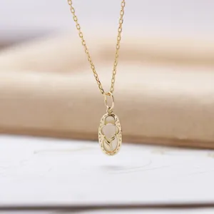 Close-up of elegant gold-plated oval pendant with pink gem inlay on a delicate chain