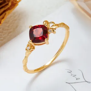 Macro view of gold-plated silver ring featuring cushion-cut red stone and ribbon detail