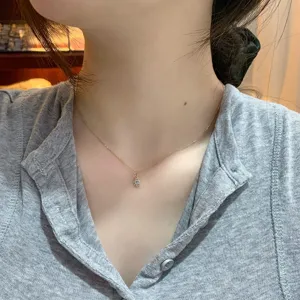 Dettaglio di una collana dorata s925 con ciondolo in acquamarina indossata da una modella.