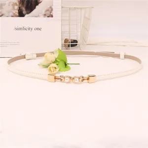 Close-up van de elegante witte smalle riem met een metallic parelgesp detail voor jurken.