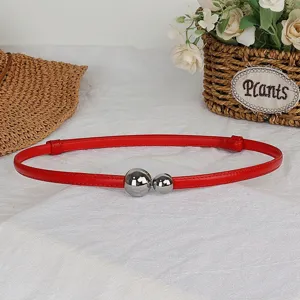 Detailed view of red thin women belt featuring silver dual sphere buckle for dress.