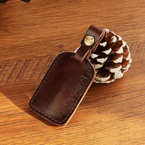 Close up detail of dark brown leather badge holder keychain with brass screw rivet and pinecone.