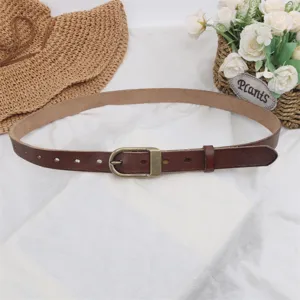 Detail shot of a slim genuine leather women's belt with vintage metal buckle for jeans.