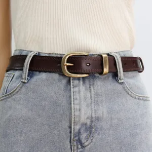 Close-up view of dark brown leather belt with vintage brass buckle worn on denim jeans.