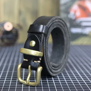 Close-up of black genuine leather belt with classic brass metal buckle detail texture view