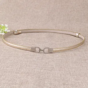 Détail rapproché de la fine ceinture dorée élégante pour femme avec boucle métal.