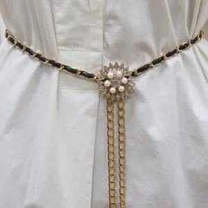 Closeup detail of women's waist chain, black leather gold chain with pearl rhinestone flower.