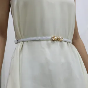 Detail view of a sweet pearl double-buckle thin belt accessory worn on a stylish dress.