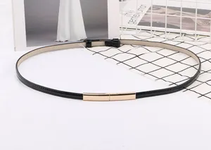 Vue détaillée de la fine ceinture noire vernis pour femme avec boucle en métal doré.