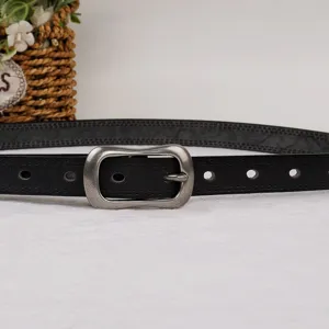 Detail shot of black leather belt buckle, classic vintage pin design for casual trousers.
