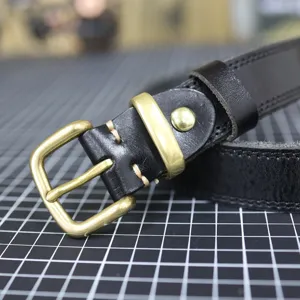 Close-up of black genuine leather belt with vintage brass buckle and contrast stitching.