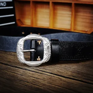 Close-up of retro carved metal belt buckle and genuine cowhide leather texture details.