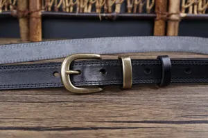 Close-up detail of women's black genuine leather belt with antique brass buckle.
