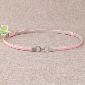Gros plan détaillé d'une fine ceinture en cuir rose minimaliste avec boucle en métal argenté.