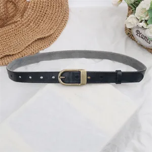 Detailed view of women genuine leather belt with vintage brass pin buckle and black strap.