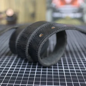 Black genuine leather belt detail shot showing fine stitching and classic pin holes.
