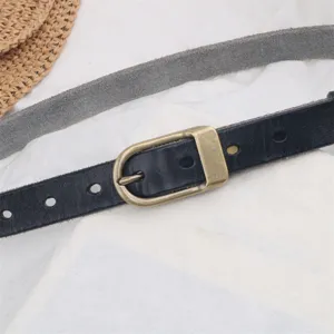 Women leather belt detail close up, classic black strap with bronze metal pin buckle.
