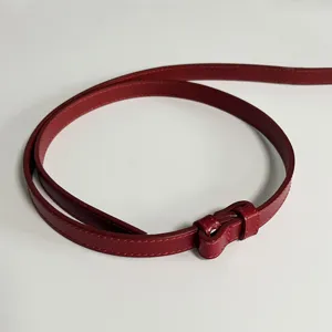 Detailed view of a red leather thin belt showcasing fine stitching and smooth texture.