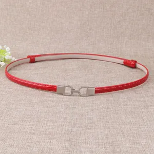 Détail de ceinture fine en cuir verni rouge, avec boucle métallique argentée élégante.
