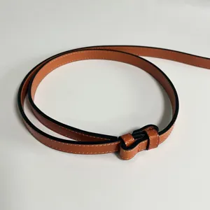 Close-up detail of a thin brown genuine leather women dress belt with contrast white stitching.