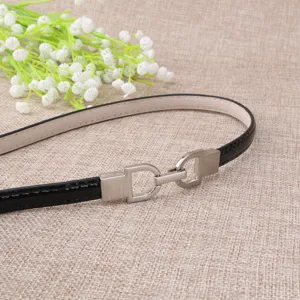 Ceinture fine en cuir vernis noir pour femme avec boucle dorée argentée, accessoire élégant.