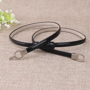 Vue détaillée de la fine ceinture en cuir vernis noir avec boucle métallique brillante.