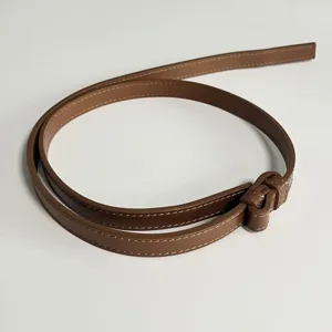 Close-up of brown leather belt with fine stitching details, perfect accessory for dresses.