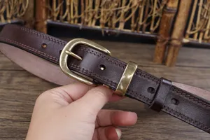 Close-up of brown genuine cowhide leather belt with retro metal buckle for women daily wear.