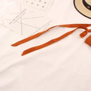 Vista detallada del elegante cinturón de ante camello con textura suave y tiras largas.