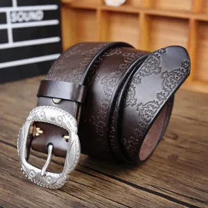 Close-up detail of vintage embossed brown leather belt with ornate silver pin buckle.