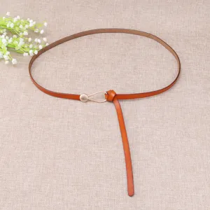 Detail view of a thin brown leather belt featuring a delicate droplet metal buckle on fabric.