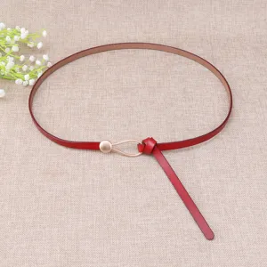 Red thin leather belt with metal teardrop buckle, stylish accessory for dresses and jeans.