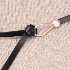 Detail shot of black leather belt featuring a chic gold teardrop metal buckle and loop.