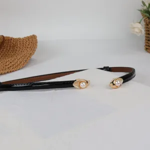 Detailed view of sweet slim black patent leather belt with elegant pearl gold buckle.