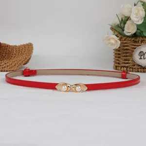 Red thin patent leather belt with elegant pearl gold buckle, perfect detail shot for women.