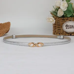 Detailed view of women's silver thin waist belt featuring elegant gold pearl buckle design.