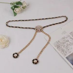 Detail view of a luxury gold chain belt featuring black leather weave and pearl flower pendants.