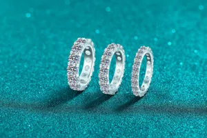 Dettaglio di tre scintillanti anelli eternity in moissanite di diverse larghezze
