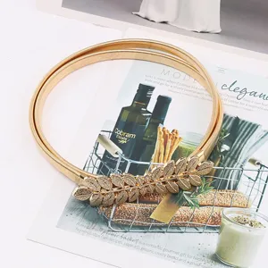 Detail view of the elegant gold metallic stretch waist chain showcasing the delicate leaf buckle.