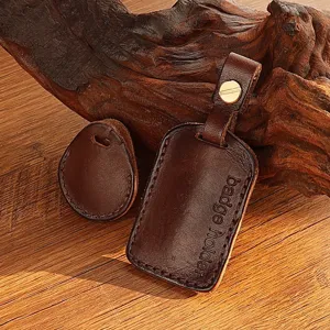 Close-up of handmade dark brown leather badge holder and teardrop key cover detail view.