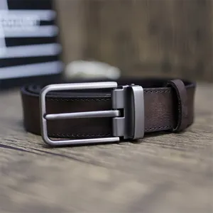 Detailed close-up of men's genuine leather belt, vintage brown cowhide with metal pin buckle.